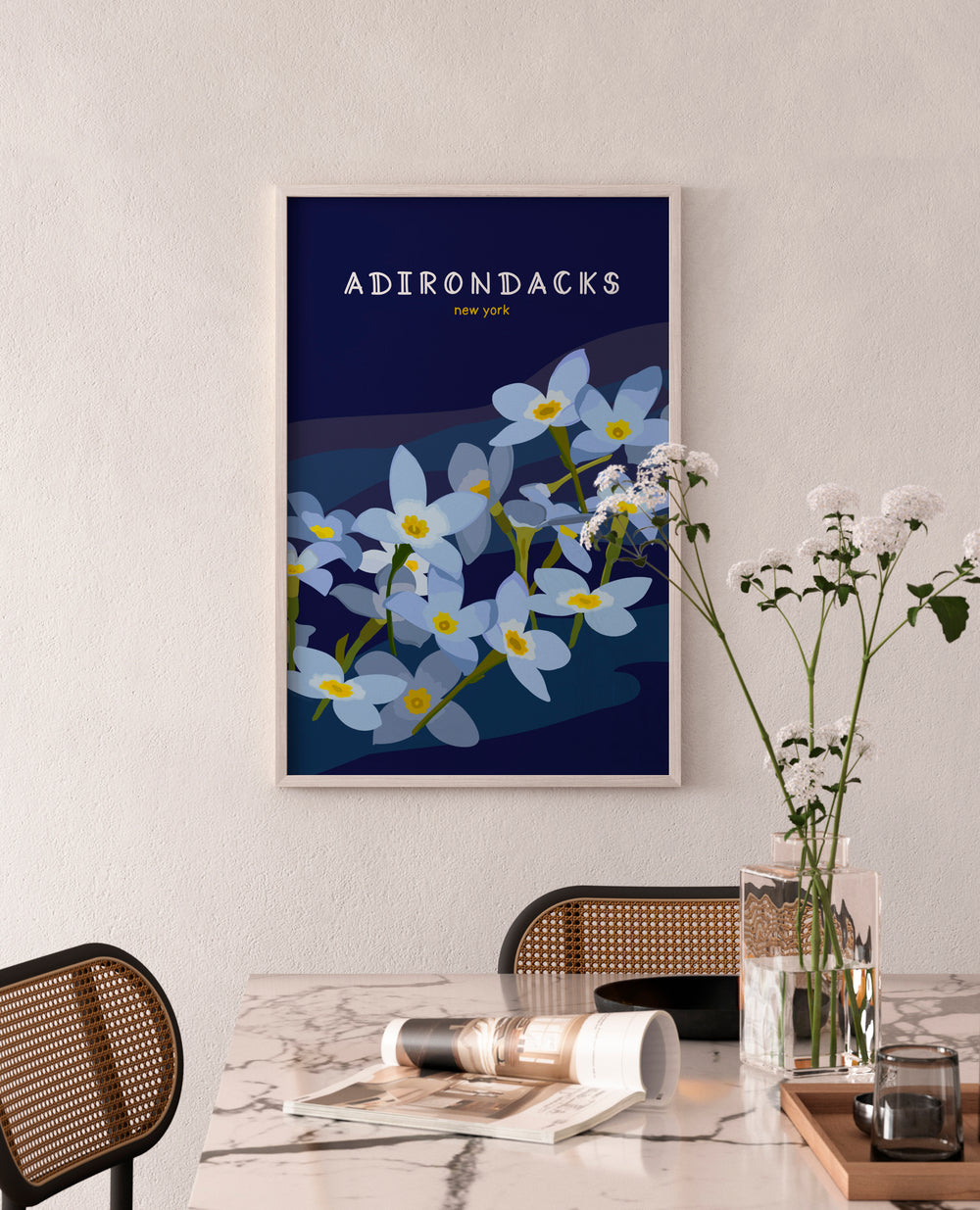Framed artwork with floral design and 'Adirondacks New York' text on a wall above a dining table.