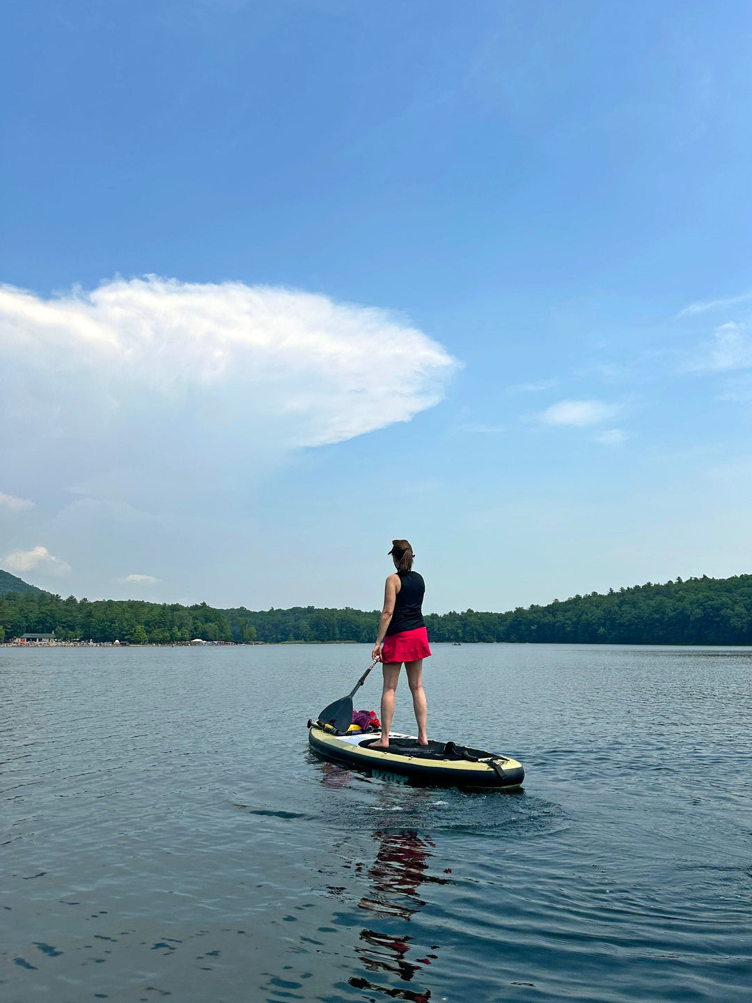 Person paddleboarding on a calm lake with a clear blue sky