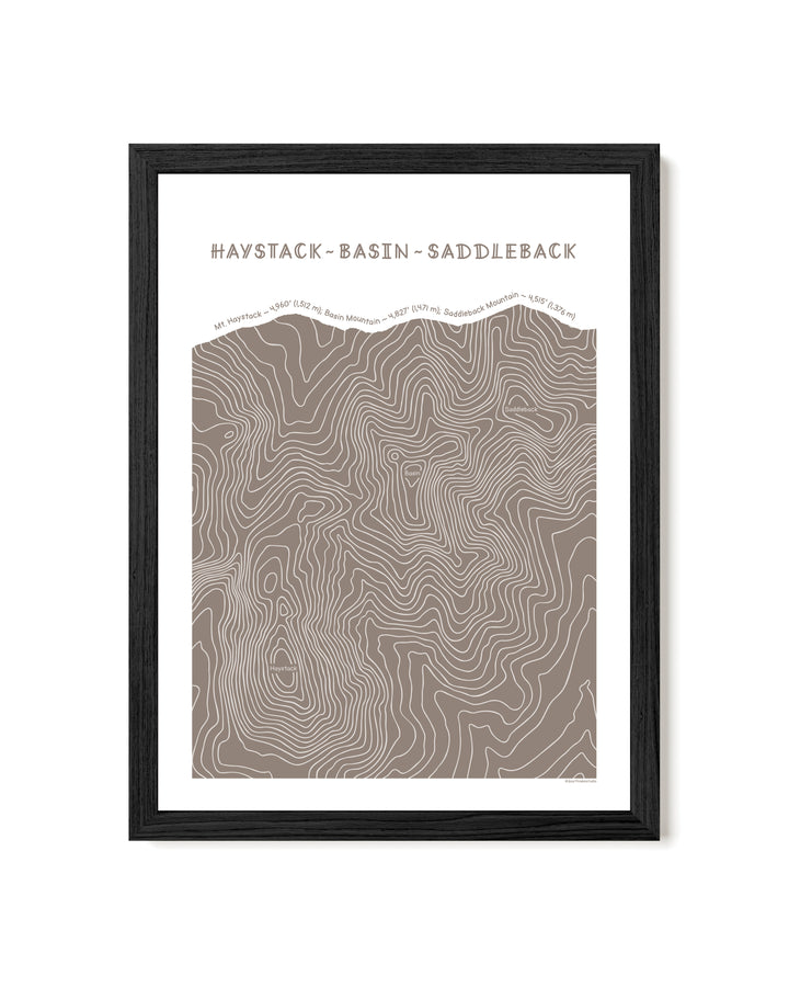 Black framed topographic map art of Haystack, Basin and Saddleback peaks in brown line patterns on a white background