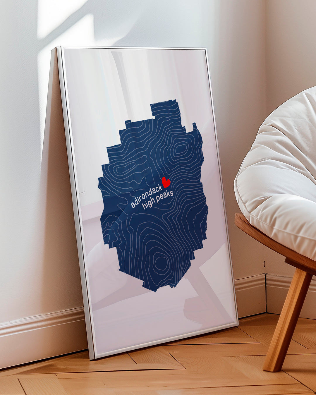 framed version mock up of simple graphic illustration of the Adirondack park outline filled with contour lines and the words Adirondack High Peaks.